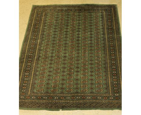 A Bokhara style rug, the central panel set with five rows of repeating elephant foot medallions on a jade ground, within a st