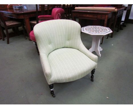 A circa 1890 ebonised armchair on turned legs and black ceramic castors, green striped upholstery