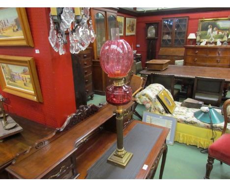 A Victorian brass column oil lamp, cranberry glass sump and shade, 80cm high 