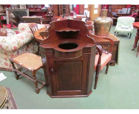 An early Victorian flame mahogany corner washstand, the raised back over a ceramic wash bowl insert and single door cupboard,