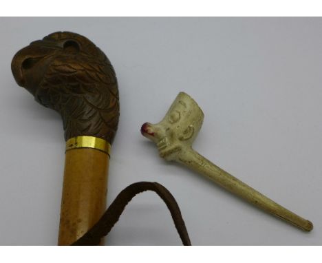 A carved walking stick top in the form of a parrot, one glass eye lacking and a novelty clay pipe