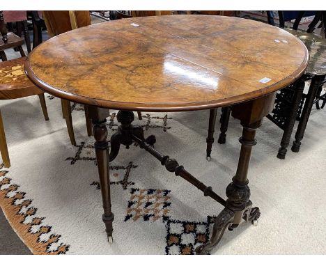 Victorian walnut veneered oval drop leaf side table raised on turned column with outswept legs and ceramic casters, 89cm wide