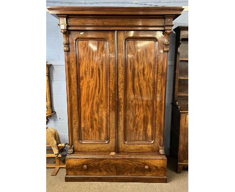 A large Victorian mahogany wardrobe with architectural cornice over two panelled doors and a base, 222cm high, 154cm wide, 70