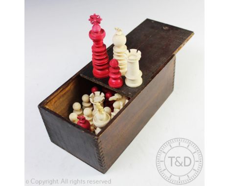 A 19th century 'Lund' style ivory chess set within stained pine box, comprising sixteen red stained pieces and sixteen ivory 