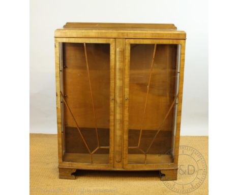 A late Art Deco walnut display cabinet, with two 'sunray' glazed doors on bracket feet, 128cm H x 100cm W x 28.5cm W (at faul