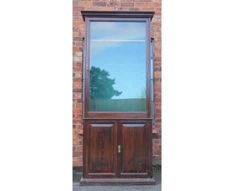 A late 19th century Army & Navy stained pitch pine gun cabinet, with glazed door above two cupboard doors enclosing three dra