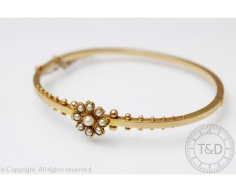 A seed pearl set hinged bangle, late 19th/early 20th century, the delicate yellow metal bangle set with a central pearl set f