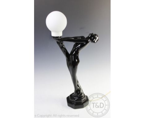 An Art Deco style figural lamp base, modelled as a nude female supporting a torch, black glazed with shade, 62cm high   CONDI