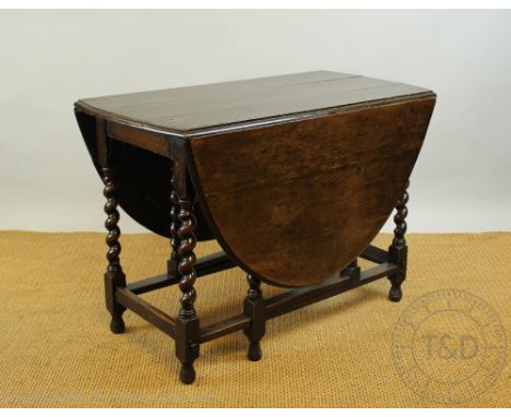 A 1920s oak gate leg table, with barley twist and block legs 74cm H x 106cm W x 55cm D.