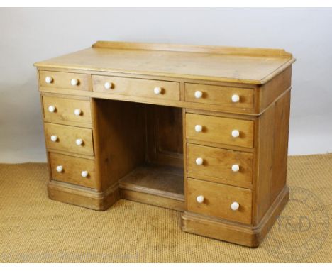 A late Victorian pine pedestal desk, with an arrangement of nine drawers with white ceramic knob handles, on plinth base, 80c