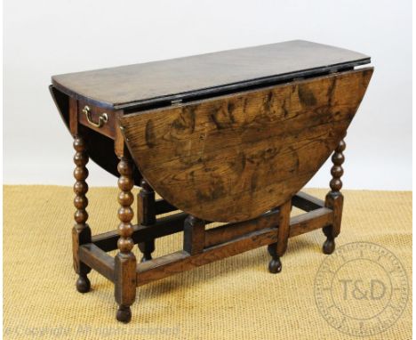 An 18th century oak gate leg table, of small proportions, the oval top above a single drawer and upon turned bobbin legs and 