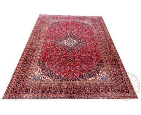 A large Persian Kashan type wool carpet, worked with an all over floral design against a red ground, 413cm x 275cm   CONDITIO