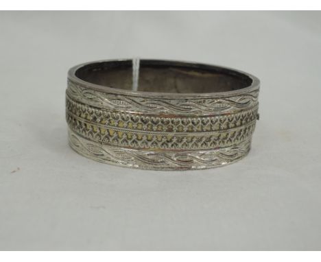 A white metal hinged bangle having engraved and wire decoration, no marks 