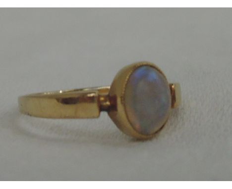 A ladies dress ring having an oval opal in a milgrain mount on a yellow metal loop, no marks