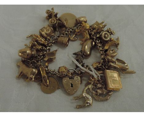 A 9ct gold belcher chain charm bracelet having a padlock clasp and 34 x 9ct gold charms including vintage tractor, goat, skie