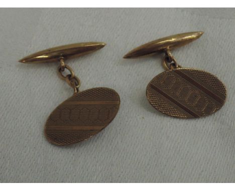 A pair of 9ct gold cufflinks having oval fronts with engine turned decoration and lozenge backs with chain spacers, Chester h