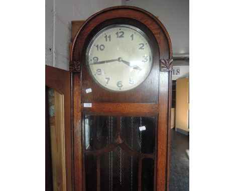 A 1920's oak grandmother clock having arch top and circular dial on glass trunk and step base