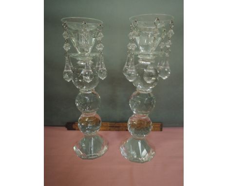 A pair of modern glass candlesticks of facetted bobbin design having plastic lustre drop sconces