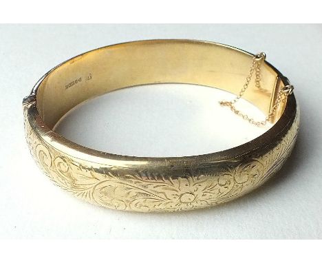A 9ct gold hinged bangle, c1960's, with engraved scroll decoration, 1.6cm wide, internal dimensions 6.2cm x 5.8cm, 22g.