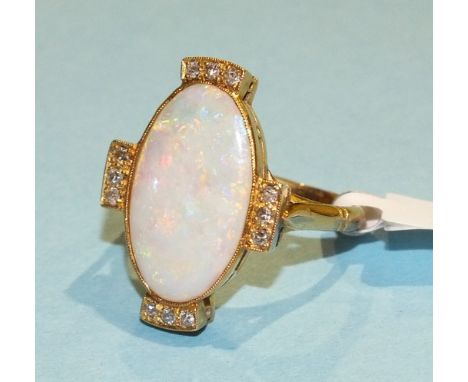 An opal and diamond cluster ring, the large oval opal (19 x 11.5mm), millegrain-set with trios of 8/8-cut diamonds above, bel