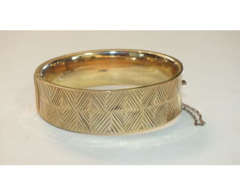 A 9ct gold hinged bangle with engraved geometric decoration, 27g.