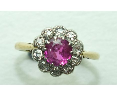 An Edwardian ruby and diamond cluster ring claw-set a round-cut ruby within a surround of ten old brilliant-cut diamonds, in 