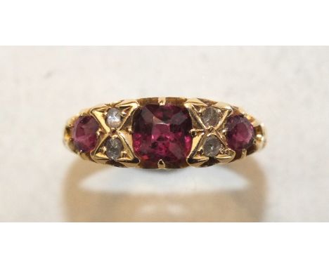 An 18ct yellow gold ring set three garnets, with pairs of rose-cut diamonds between, size K, 3.4g.