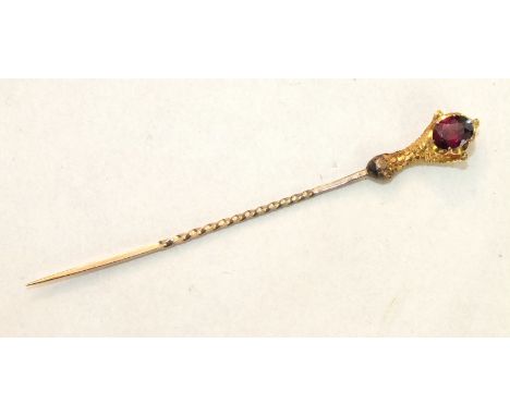 A stick pin in the form of a talon holding an oval garnet, unmarked.