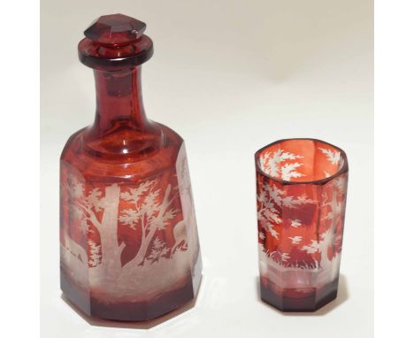 Bohemian style ruby glass decanter and octagonal shaped beaker, the glass finely engraved with a deer, the beaker with a hunt