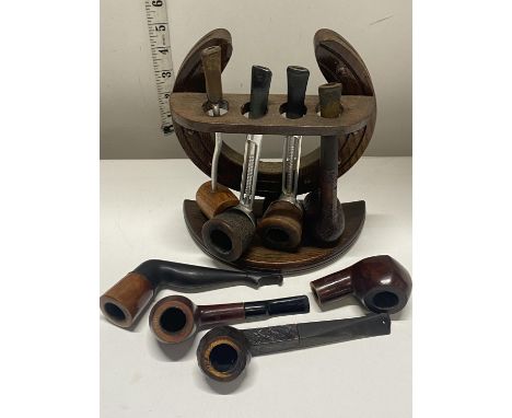 A vintage wooden pipe rack in the form of a horse shoe with a selection of wooden pipes