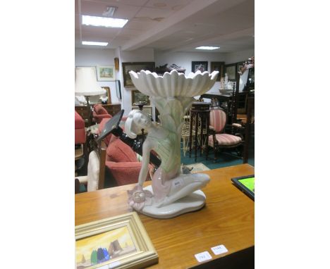 A CONTINENTAL PORCELAIN FIGURAL PLANTER modelled as a young girl shown reclining holding a scallop shaped bowl aloft