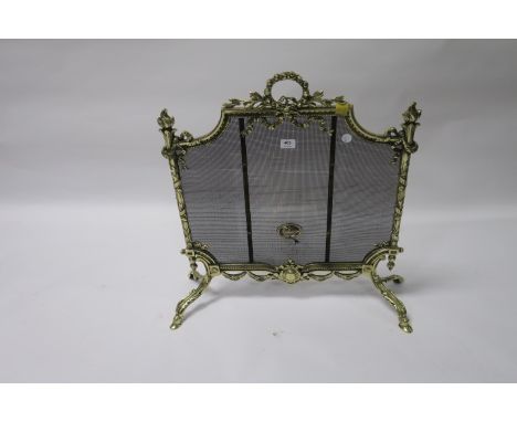 A GEORGIAN STYLE BRASS FRAMED FIRESCREEN the shield shaped top centred by a ribbon tied bouquet and draped with swags above a
