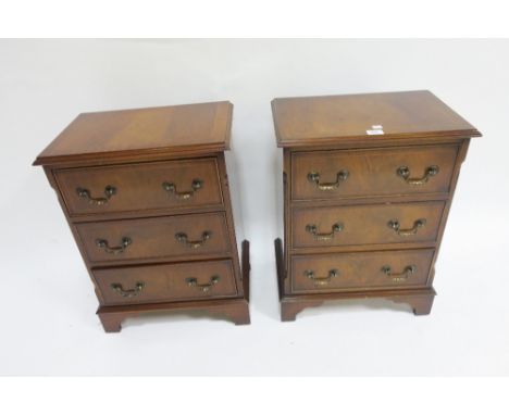 A PAIR OF GEORGIAN STYLE CHESTS the rectangular tops with moulded rim above three short drawers brass drop handles on shaped 