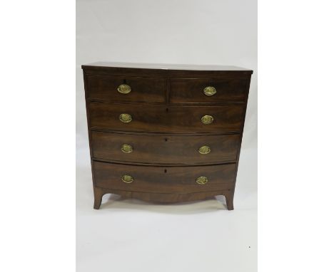 A GEORGIAN MAHOGANY BOWED CHEST OF DRAWERS the rectangular top above two short and three long cock beaded drawers with oval b