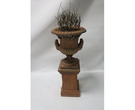 A PAIR OF TERRACOTTA CAMPANA SHAPED URNS with egg and dart border above the waisted body applied with foliates on a circular 