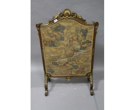 A CONTINENTAL STYLE MAHOGANY AND GILT FRAMED FIRE SCREEN of shield shaped form the molded frame carved with foliate motifs ab