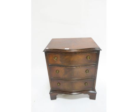 A GEORGIAN STYLE MAHOGANY BACHELOR'S CHEST of serpentine outline the plain top with moulded rim above three drawers with shap