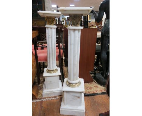 A PAIR OF WHITE MARBLE AND GILT BRASS MOUNTED PLINTHS in the form of a classical column. The square top above the reeded stem