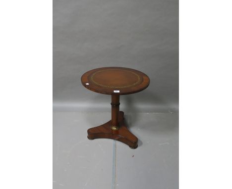 A MAHOGANY LEATHER TOOLED LOW TABLE the circular top raised on a column support with gilt brass mount on triform plinth with 