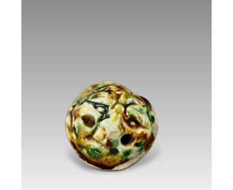 moulded in human-head shape, two holes pierced at cheek and one hole on the top, face covered in amber, green and white glaze