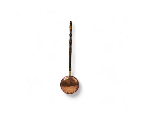 A late 19th century copper warming pan - of typical circular form, with a turned wooden handle, 102cm long.