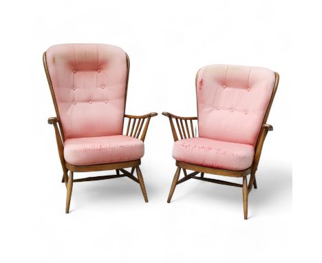 A pair of vintage Ercol beech and elm wing armchairs - with a shaped spindle back, webbed seats and turned legs joined by an 