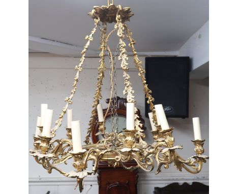 An early 20th century gilt Rococo revival multibranch chandelier with brass hanging chains cast in a floral foliate motif, 80
