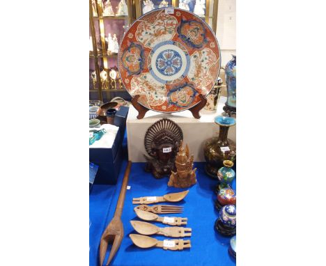 A large Imari charger decorated with cranes, two carved wooden heads, tribal carved wooden spoons and comb and a double prong