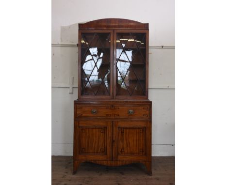 A Regency mahogany secretaire with ebony inlaid pediment above astragal glazed doors opening to reveal three interior shelves