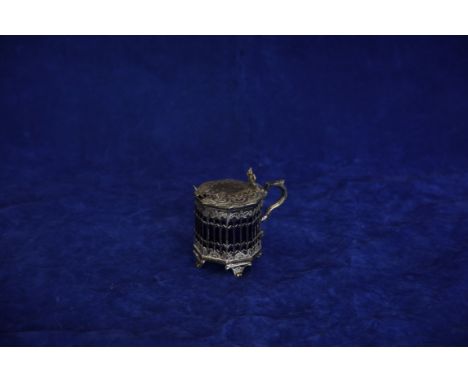 A Victorian silver mustard pot and cover of octagonal form with angular capped handle, pierced scrolled thumb piece and scrol