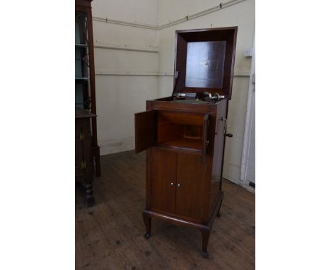 An Avonia record player in a mahogany case with hinged lid above two cupboard doors opening to reveal the speaker and above t
