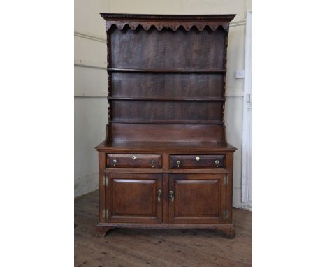 A George III Irish dresser in oak with Greek key pediment above a shaped frieze and three shelves.  The base with two long dr