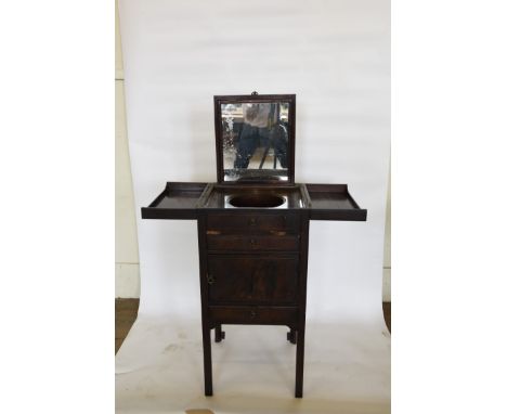 A Georgian mahogany washstand with fold-out top opening to reveal a circular aperture and pull-up mirror above a simulated fr