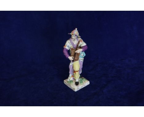 A continental porcelain figure of an oriental musician wearing a multi-coloured feather hat, playing a Chinese instrument and